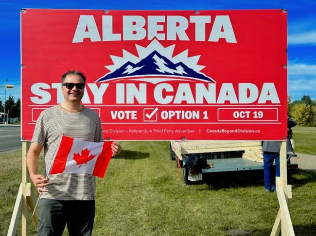 Volunteer beside a Stay in Canada billboard
