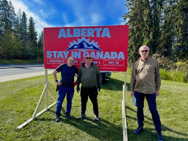 Volunteers together beside a billboard