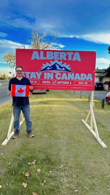 Volunteer beside an installed Stay in Canada billboard