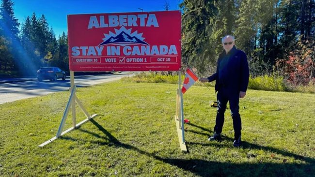 Volunteer beside a Stay in Canada billboard