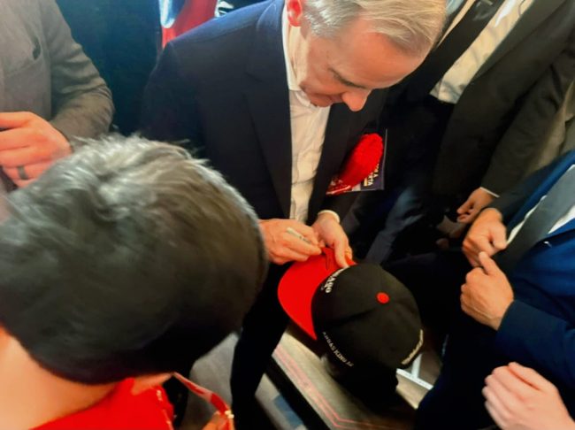 Signing a young attendee’s hat